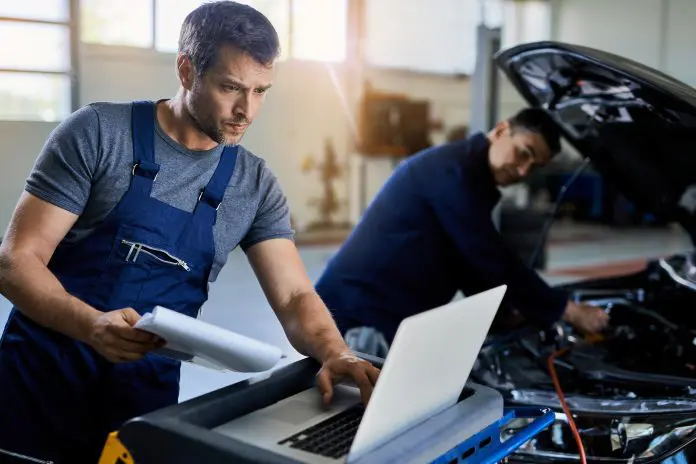 mid-adult-mechanic-using-laptop-car-diagnostic-while-working-with-colleague-auto-repair-shop-696x464